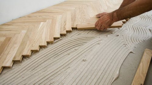 Carpenter on work putting wood parquet pieces. Home construction Carpenter on work putting wood parquet pieces. Home construction