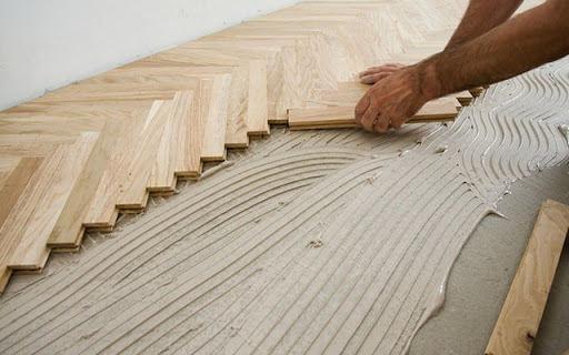 Carpenter on work putting wood parquet pieces. Home construction